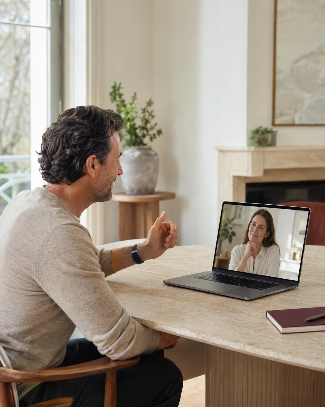 A man at a table speaking with a woman on a video call